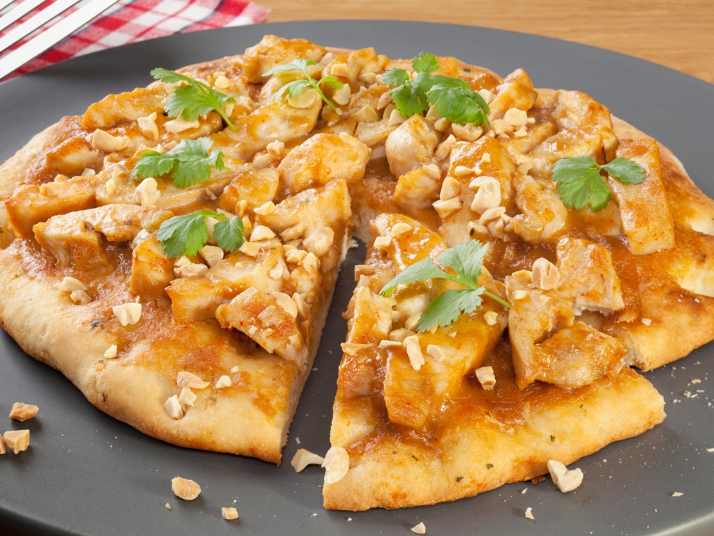 Pizza with satay chicken topped with coriander and roasted peanuts
